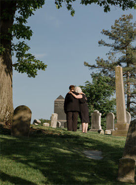 Women Hugging At A Gravesite
