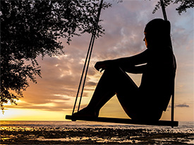 Woman sitting on a swing watching the sunset