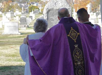 priest with family at cemetery